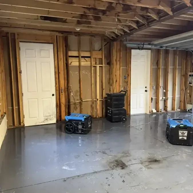 Dehumidifiers running in a gutted lower level during a water damage dry-out
