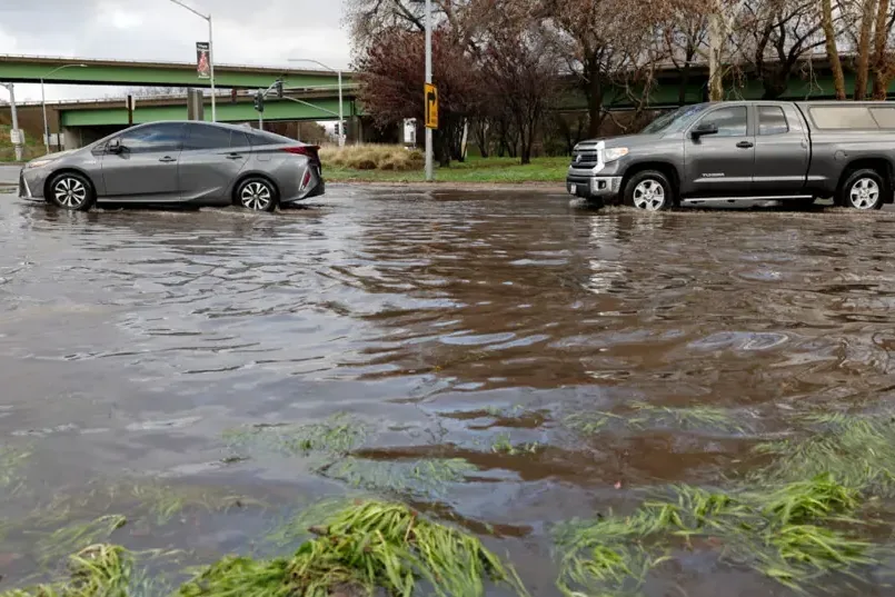 Cars driving slowly through a flooded street in heavy rain
