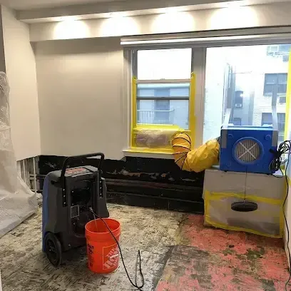 Dehumidifier and blue air mover drying a room with its flooring stripped out