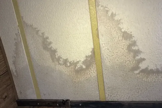 Water stain spreading across a ceiling from a leak above